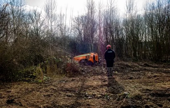 Funkraupe auf einem Waldweg, Bediener steuert das Gerät aus Entfernung