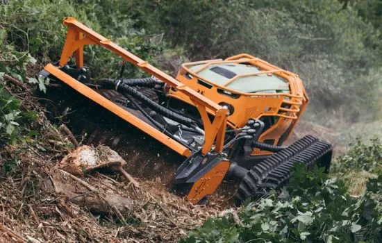 Funkraupe mit angehobenem Mulchkopf beim Arbeiten an einem Wurzelstock