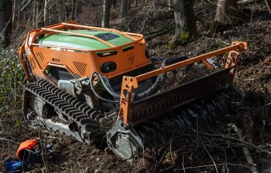 Funkraupe mit Forstmulcher auf einer Böschung zwischen Bäumen